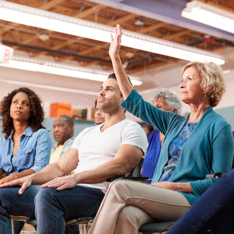 woman raising hand at community meeting