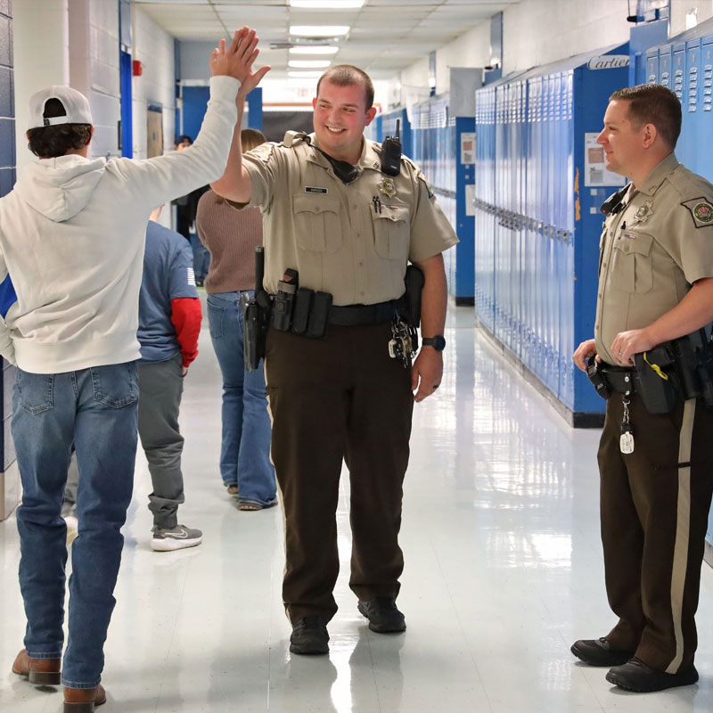 sros in the school hallway high-fiving a student at the high school